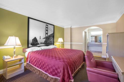 Pokój hotelowy z łóżkiem i krzesłem w obiekcie Super 8 by Wyndham Hayward Downtown w mieście Castro Valley