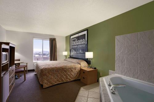a hotel room with a bed and a bath tub at Super 8 by Wyndham Corydon in Corydon