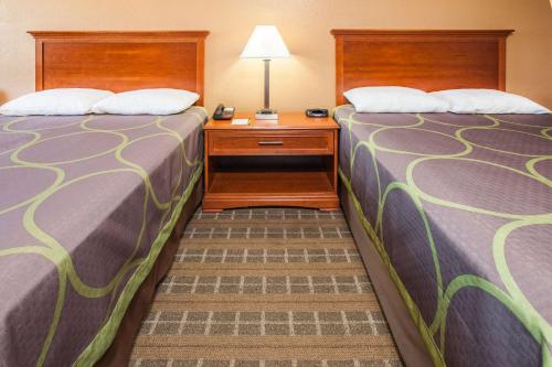 two beds in a small room with a table and a lamp at Super 8 by Wyndham Clinton in Clinton
