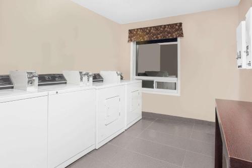 a white kitchen with white cabinets and a window at Super 8 by Wyndham Brandon MB in Brandon