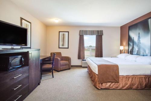 ein Hotelzimmer mit einem Bett und einem Flachbild-TV in der Unterkunft Super 8 by Wyndham Meadow Lake in Meadow Lake