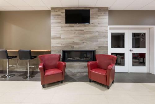 a waiting room with two red chairs and a fireplace at Super 8 by Wyndham Mont Laurier in Mont-Laurier