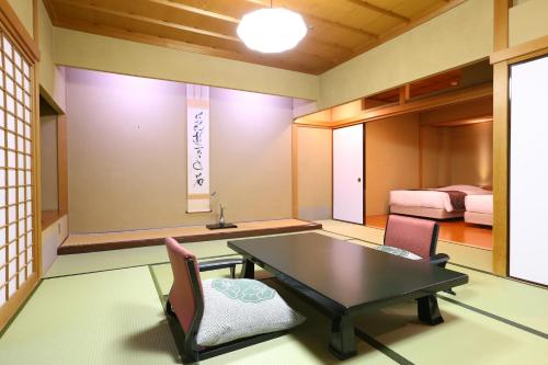 a room with a table and chairs and a bed at Oku Yugawara Tsubaki in Yugawara