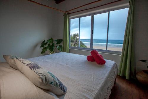 a bedroom with a bed with a view of the ocean at Pura Vida Tofo Beach Houses in Praia do Tofo