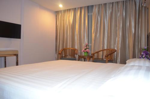 a bedroom with a large white bed and two chairs at TD Mutiara Hotel Semporna in Semporna
