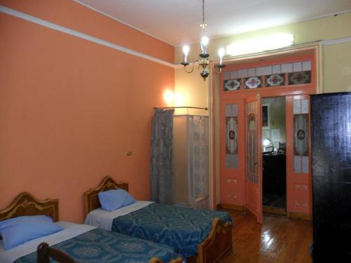 a bedroom with two beds and a hallway with a door at Berlin Hotel in Cairo