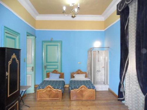 a bedroom with two beds and a blue wall at Berlin Hotel in Cairo