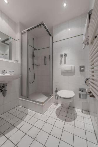a white bathroom with a shower and a toilet at Hotel Royal in Munich