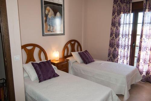 a room with two beds and a window with purple curtains at El Palacete in Setenil