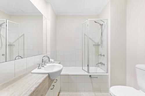 a white bathroom with a sink and a shower at Aligned Corporate Residences Kew in Melbourne