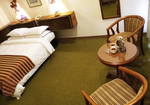 a hotel room with a bed and a table and chairs at Oriental Palace Hotel in Manama