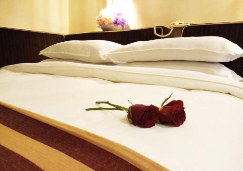 a red rose on a bed with three pillows at Oriental Palace Hotel in Manama