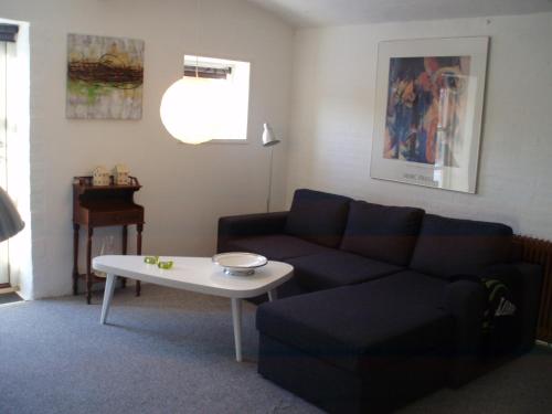 a living room with a couch and a table at Klitgaards Holiday Apartment in Mejeriby