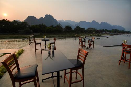 a row of tables and chairs on a patio next to a river at Inthira Vangvieng in Vang Vieng