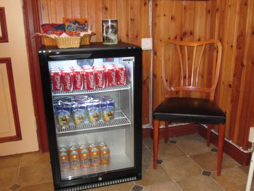 - un réfrigérateur avec des bouteilles de soda et une chaise dans la chambre dans l'établissement Sörnäsgården Bed & Breakfast, à Lima