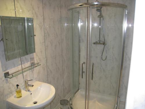 La salle de bains est pourvue d'une douche et d'un lavabo. dans l'établissement Rosebud Cottage Guest House, à Haworth