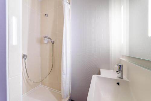 ein Bad mit einer Dusche, einem WC und einem Waschbecken in der Unterkunft B&B HOTEL Besançon Chateaufarine in Besançon