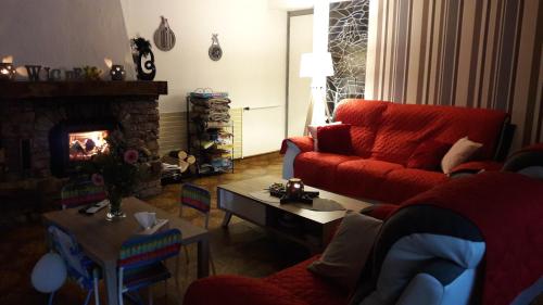 - un salon avec un canapé rouge et une cheminée dans l'établissement Chambre d'Hotes Le Saut de La Truite, à Orbey