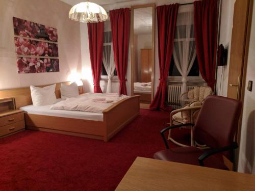 Schlafzimmer mit einem Bett mit rotem Teppich und roten Vorhängen in der Unterkunft Bahnhotel Dippoldiswalde in Dippoldiswalde
