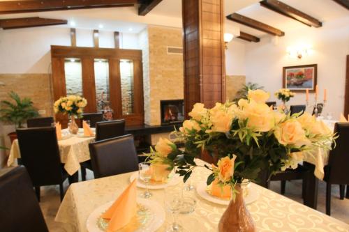 a dining room with a table with flowers on it at Hotel Roco in Izvin