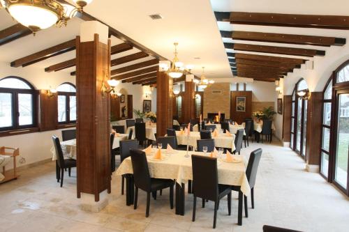 a dining room with tables and chairs and windows at Hotel Roco in Izvin