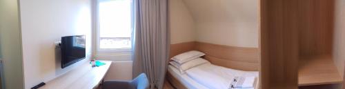 a room with a bed and a tv and a window at Landgasthof Hirschen in Hohenems