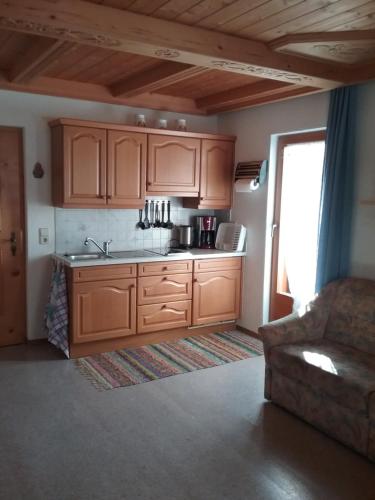 uma cozinha com armários de madeira e um sofá num quarto em Ferienwohnung Außerlechner em Kartitsch
