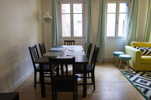 a dining room with a black table and chairs at Le 22 in Honfleur