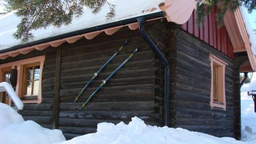 a log cabin with snow in front of it at Tomtelandstugan in Mora