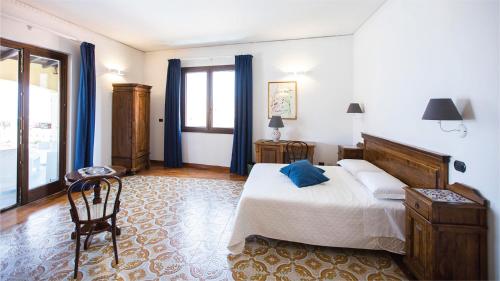 a bedroom with a large bed and blue curtains at Hotel La Piazzetta in Castellammare del Golfo