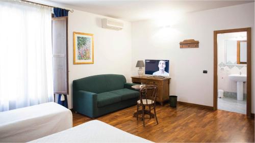 a living room with a green couch and a television at Hotel La Piazzetta in Castellammare del Golfo