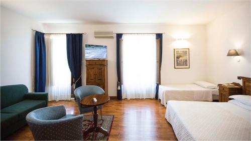 a hotel room with two beds and a green couch at Hotel La Piazzetta in Castellammare del Golfo