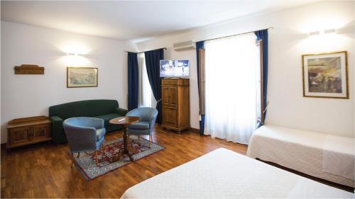 a hotel room with a bed and a couch and chairs at Hotel La Piazzetta in Castellammare del Golfo