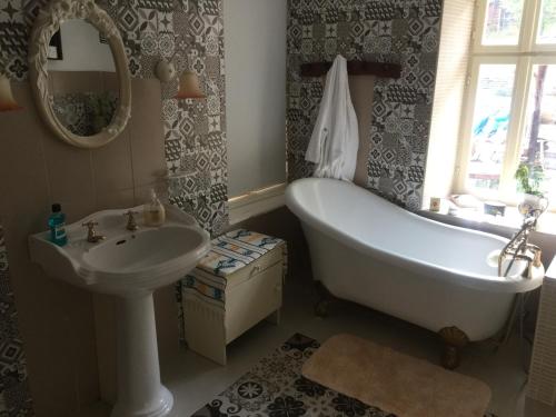 ein Badezimmer mit einer Badewanne, einem Waschbecken und einem Spiegel in der Unterkunft The Pink House in Polkownik Serafinowo