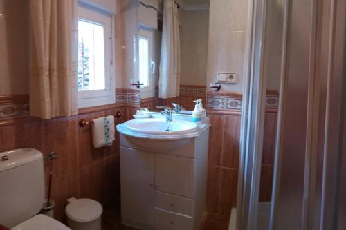 a bathroom with a sink and a toilet and a window at Casa Rural La Cucurrumacha in Navalosa