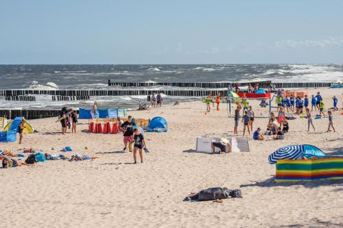 a group of people on a beach with the ocean at Dwie Sosny z sauną, Sun & Snow in Ustronie Morskie