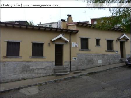 um edifício amarelo com janelas e uma porta numa rua em Casa Rural las Escuelas II em El Hoyo de Pinares