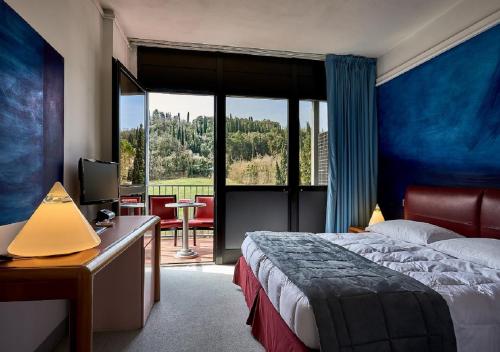 a hotel room with a bed and a desk with a television at Albornoz Palace Hotel in Spoleto