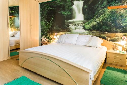 een bed in een slaapkamer met een watervalmuurschildering bij Počitniška hiša Pologar in Tolmin