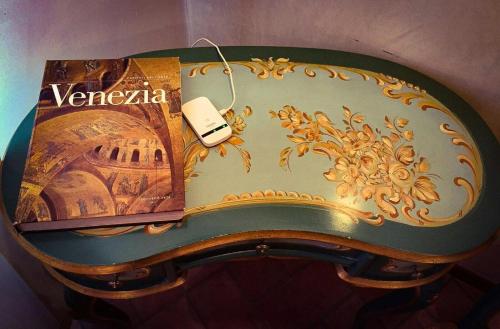 a table with a book and a cell phone on it at Suite Ai Leoni in Venice