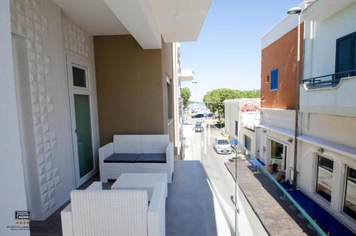 einen Balkon mit weißen Stühlen auf einem Gebäude in der Unterkunft Porto Cesareo Exclusive Room in Porto Cesareo
