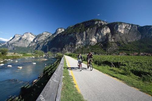 two people riding bikes on a road next to a river at B&B Perbacco Relax in Mezzolombardo
