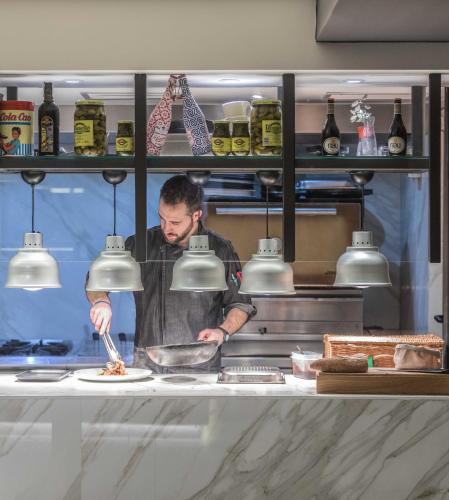 a man standing in a kitchen preparing food at INNSiDE by Meliá Palma Bosque in Palma de Mallorca