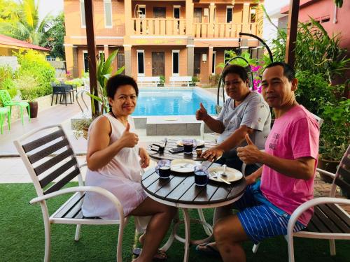 a group of three people sitting at a table at D lima beach inn in Pantai Cenang