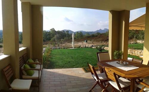 eine Terrasse mit einem Tisch und Stühlen sowie einem großen Fenster in der Unterkunft monte moro in Arzachena