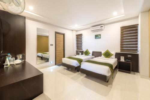 a hotel room with two beds and a desk at Treebo Raj Premier, Indiranagar in Bengaluru