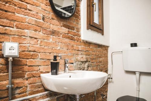 a bathroom with a white sink and a brick wall at The Hostello in Verona
