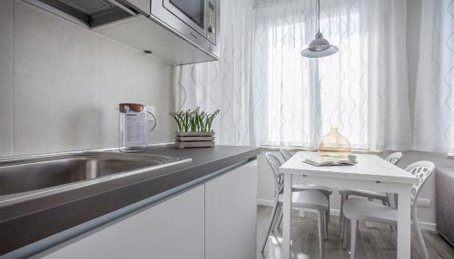 uma cozinha com um lavatório e uma mesa com cadeiras em Italianway-Cadorna 10A Flat em Milão