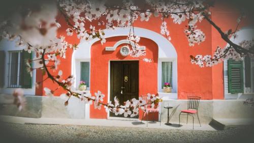 a red building with a black door and a chair at Charme of Villa Capannina in Novi Ligure