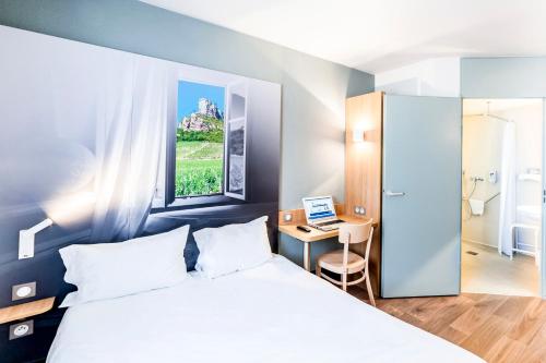a bedroom with a bed and a desk with a laptop at B&B HOTEL Chalon-Sur-Saone Sud in Saint-Rémy